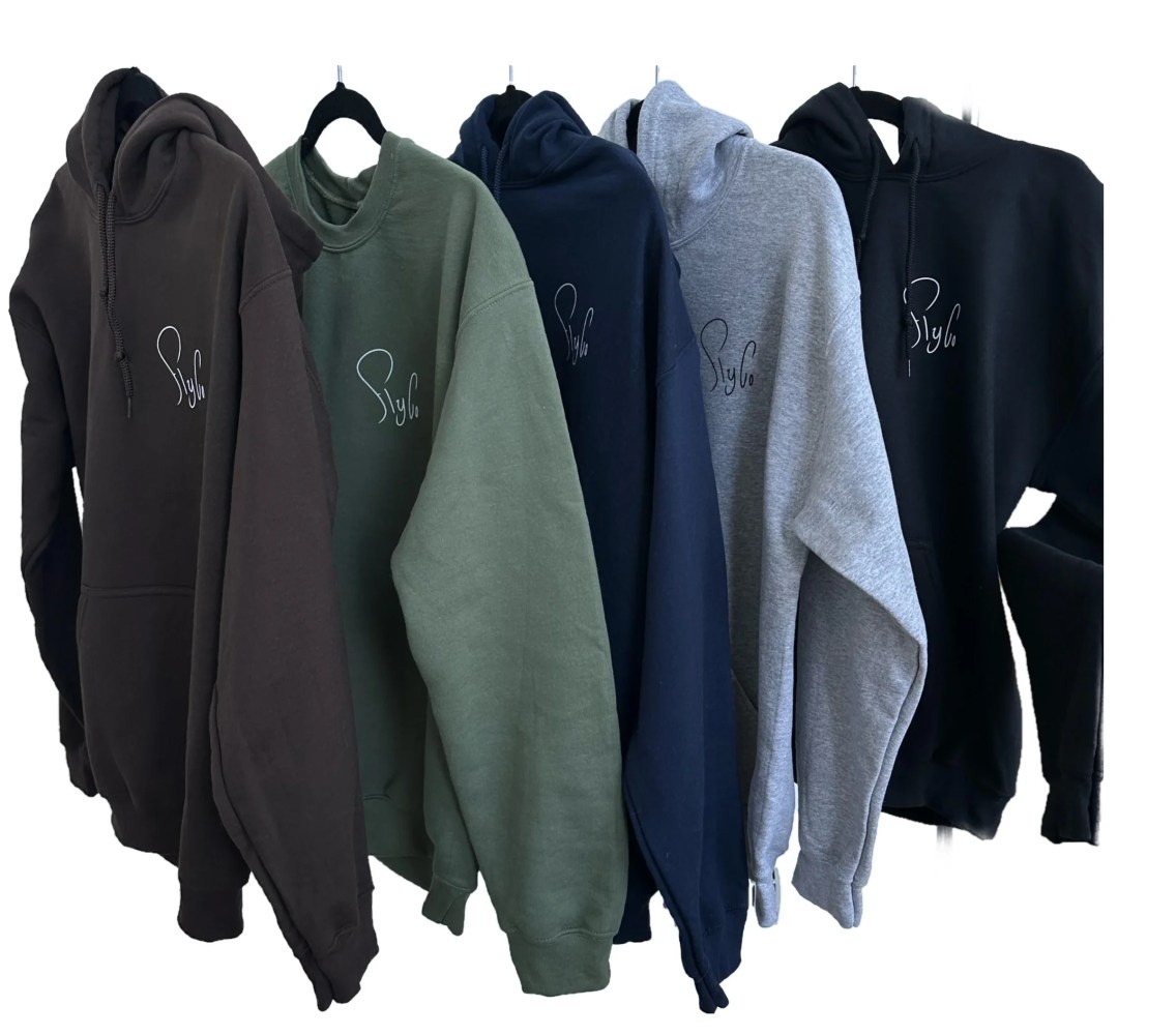 Five hoodies in brown, green, navy, gray, and black with subtle logo hung on hangers.