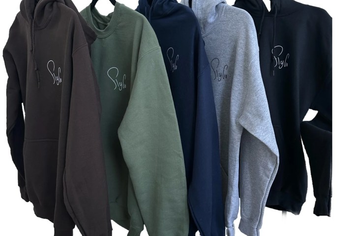 Five hoodies in brown, green, navy, gray, and black with subtle logo hung on hangers.