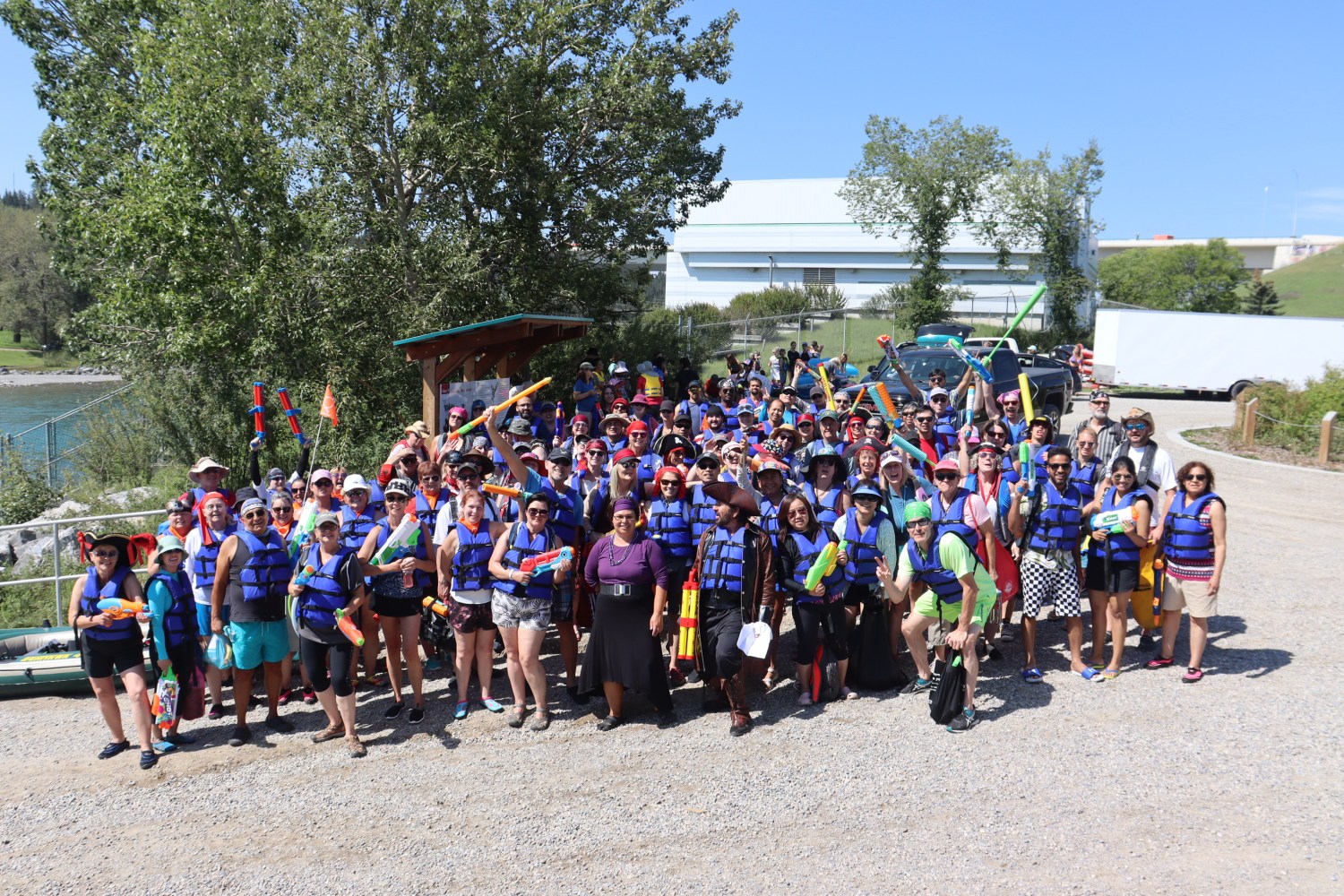Large group of guests in blue life vests posing together before a Lazy Day float.