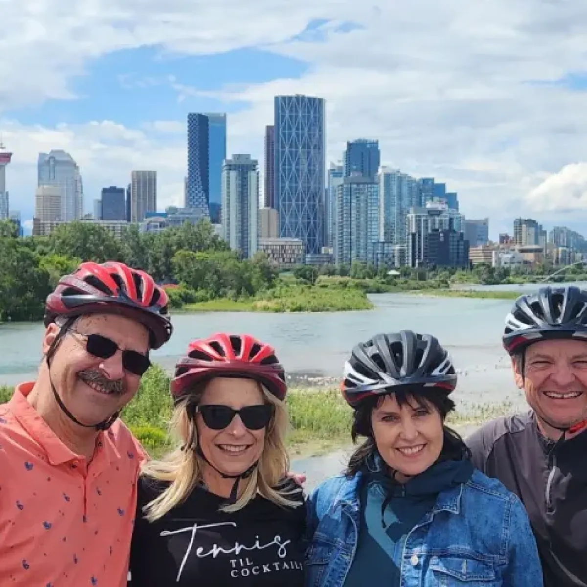 1000043065 Four people wearing helmets pose with a city skyline and river in the background.