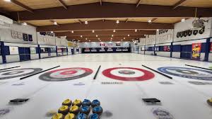 Indoor curling rink with colored target circles and stone sets on ice.