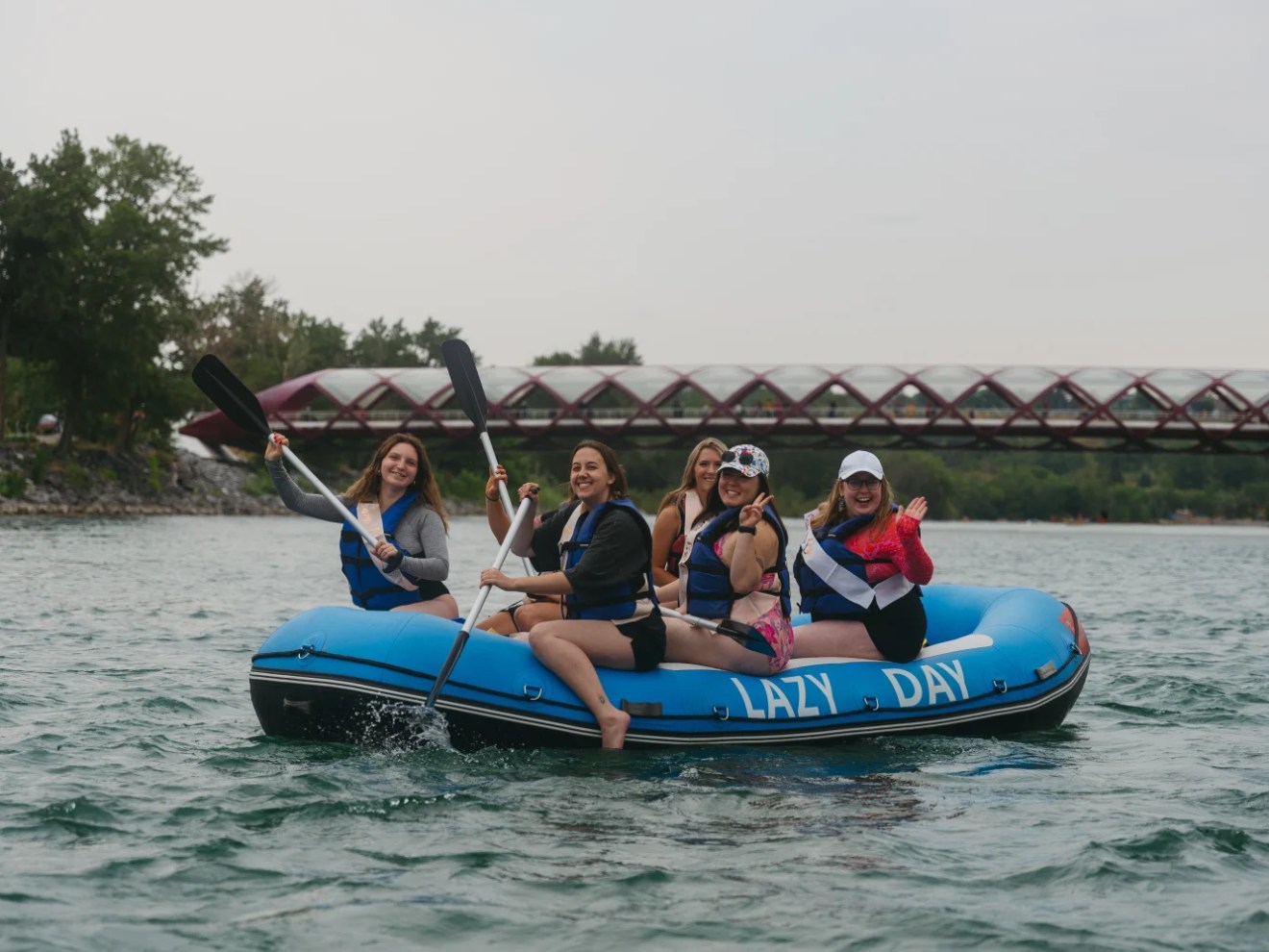 Group of women paddling on a blue raft in a river.