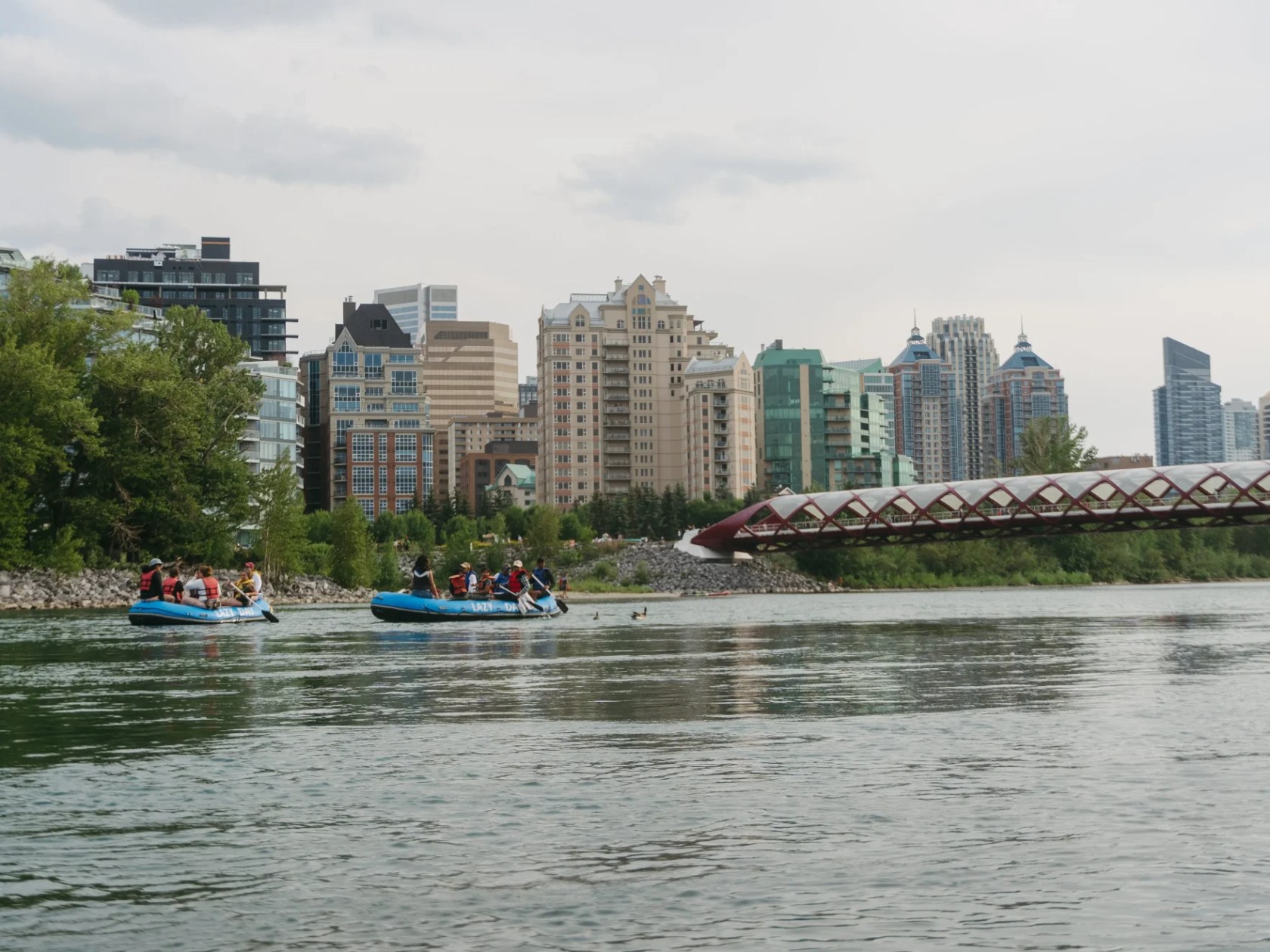 Rafting on a river with city skyline and bridge in background.