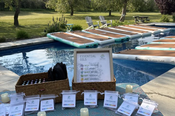 Table with name tags, sign, and gifts by a pool on a sunny day.