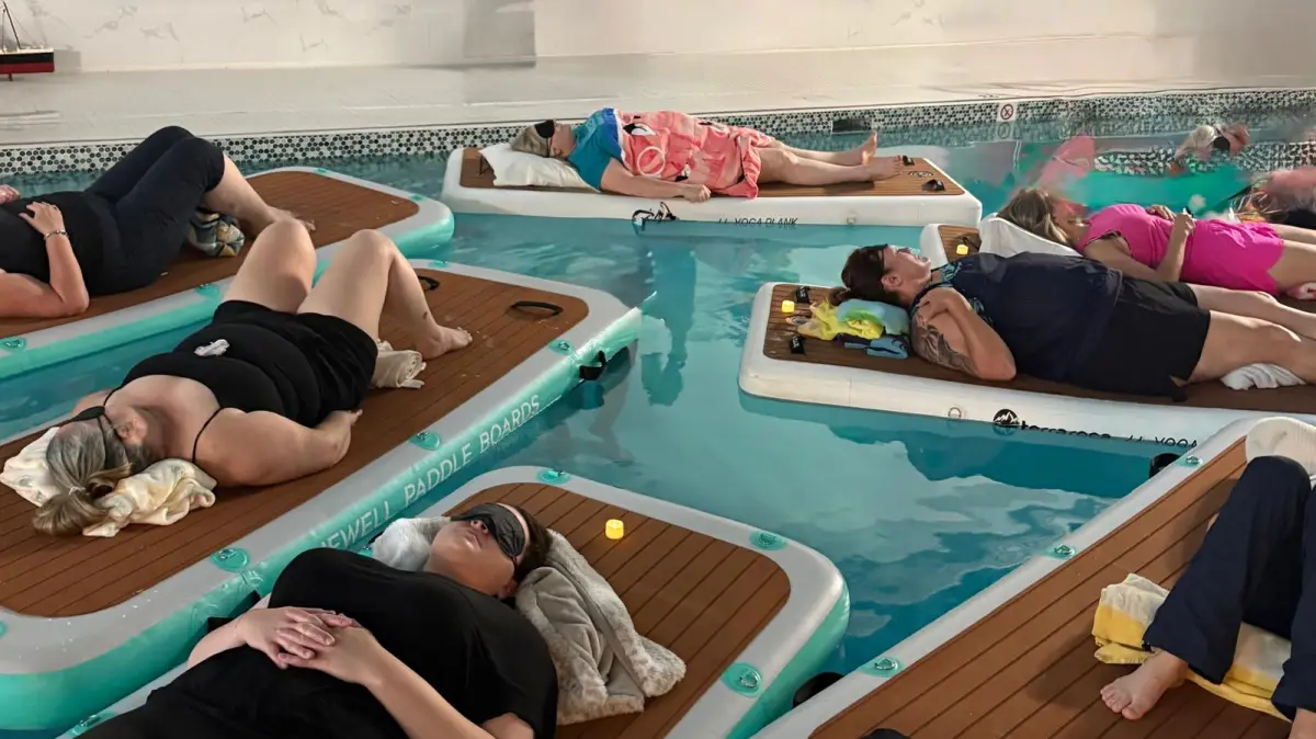 People relaxing on floating mats in an indoor pool.