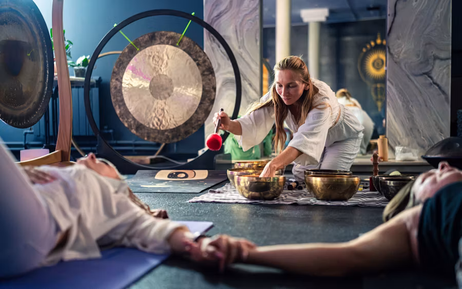 Woman conducting sound healing session with gongs and bowls.