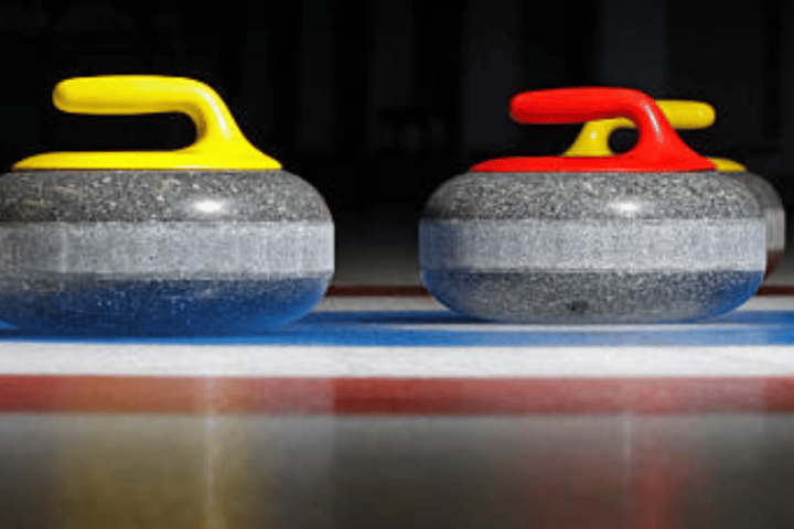 Two curling stones on ice, one with a yellow handle and one with a red handle.