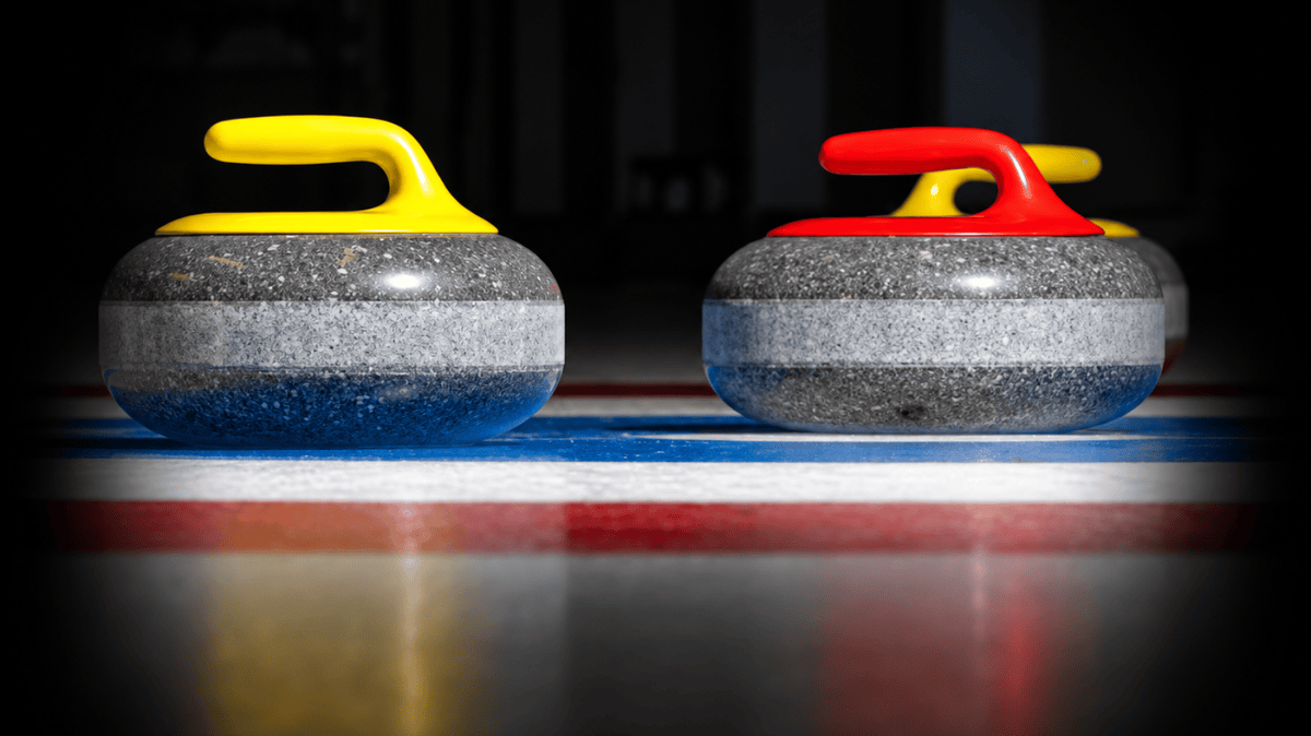 Two curling stones with yellow and red handles on ice.