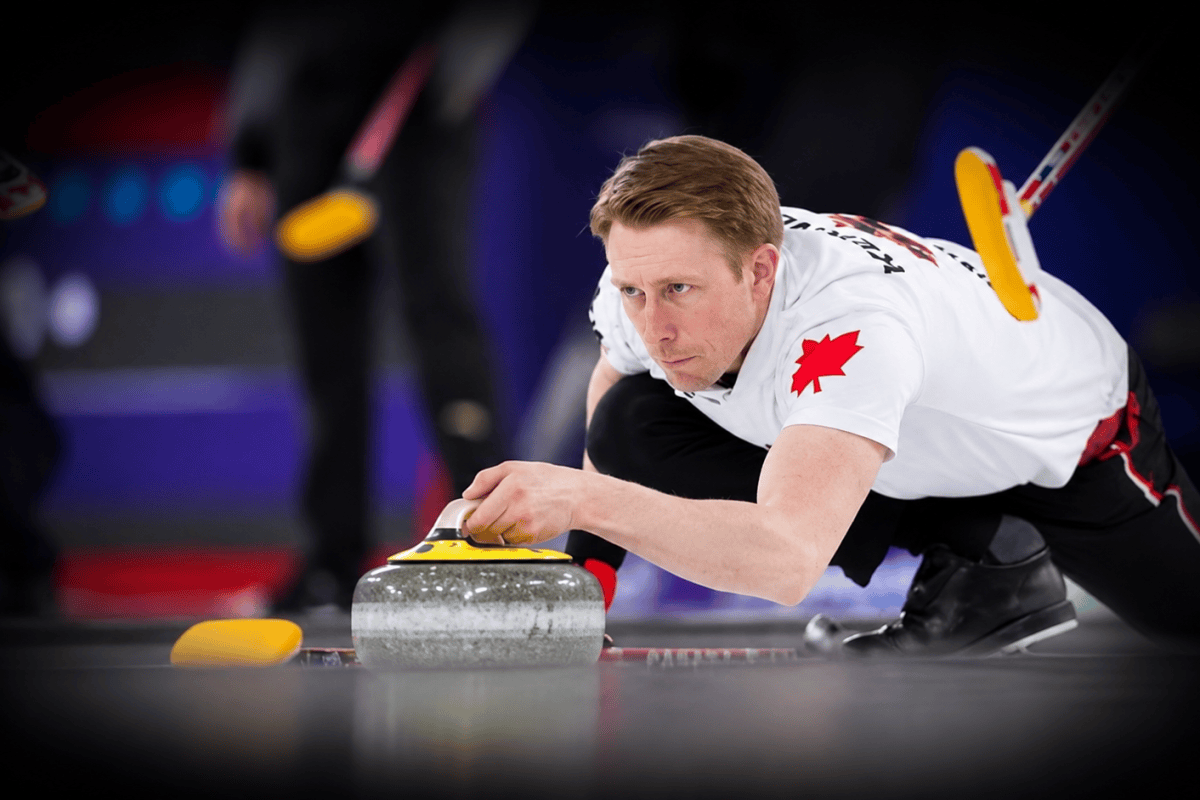 Curler in a Canada jersey focused on delivering a curling stone with a yellow handle.