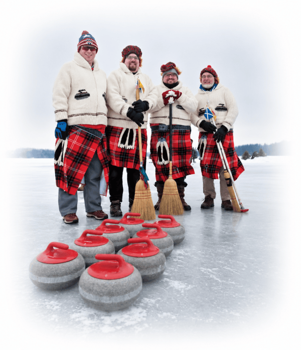 Four people in plaid kilts holding curling brooms behind a row of curling stones on a frozen lake.
