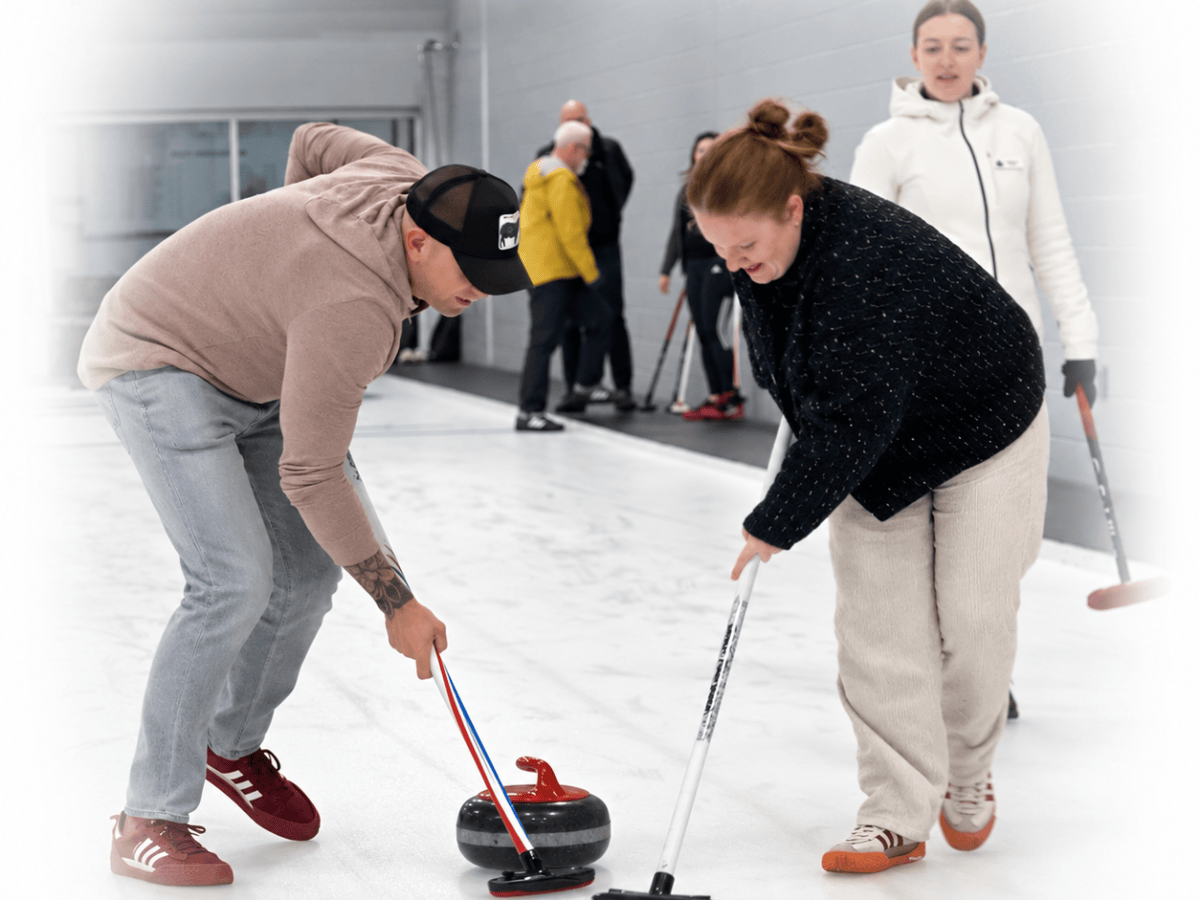 Group of people playing curling on an ice rink.