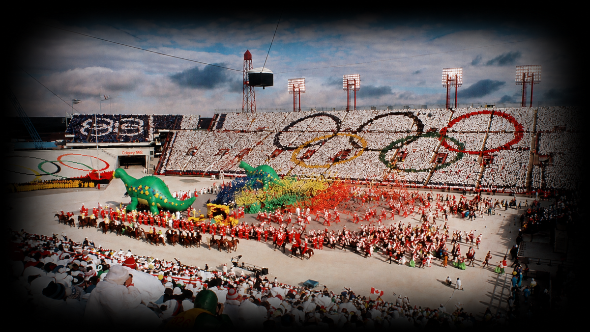 Olympic ceremony with inflatable dinosaurs and large crowd in a stadium.